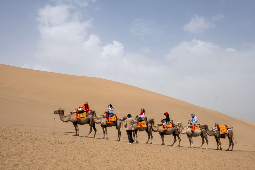 Riding camels at the Echoing Dunes, Dunhuang, China.